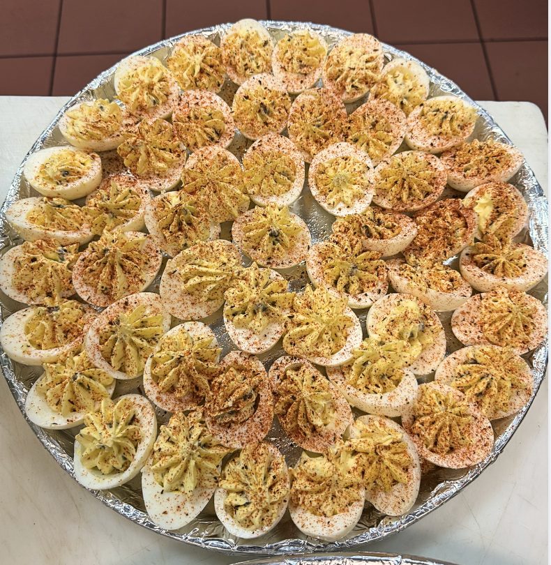 A full tray of deviled eggs dusted with paprika.
